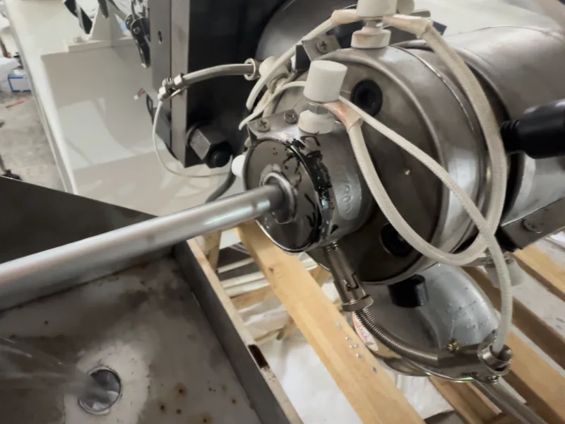 Close-up of smooth shower hose extrusion die and PVC hose running during factory test video
