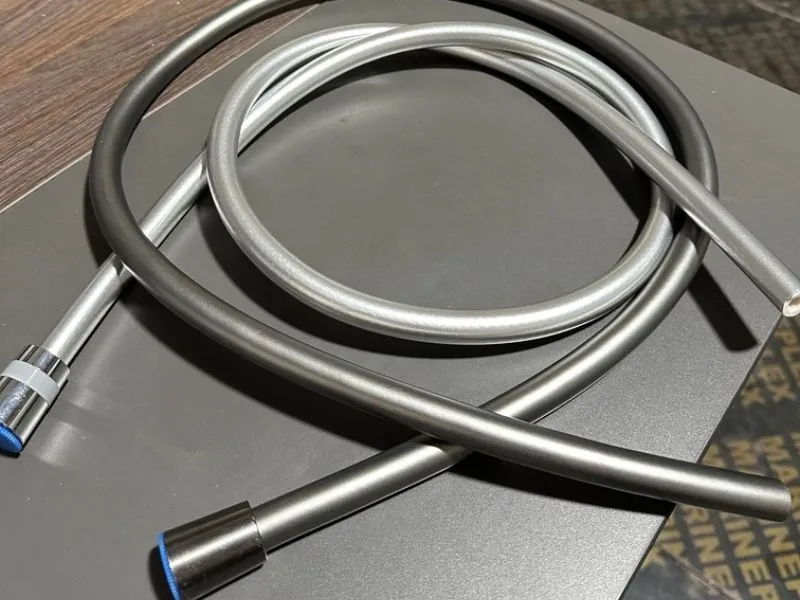 Silver and chrome-look smooth PVC shower hose sample for finish review on a shower hose extrusion line