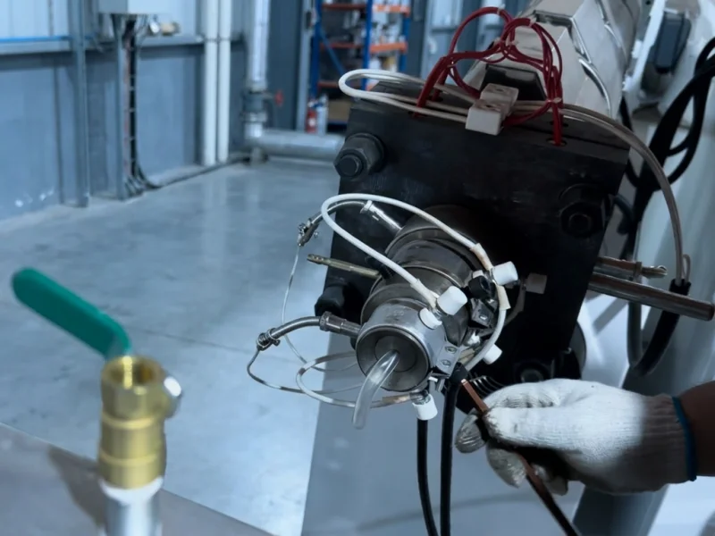 Engineer adjusting extrusion die head during PC profile extrusion line factory test run